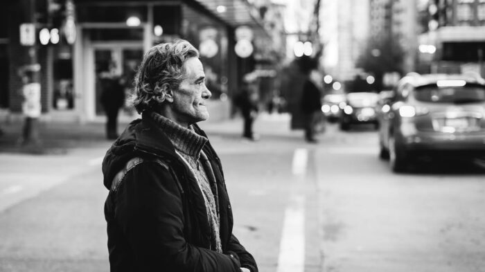 Man patiently waiting on the corner of a street with pensive peaceful demeanor