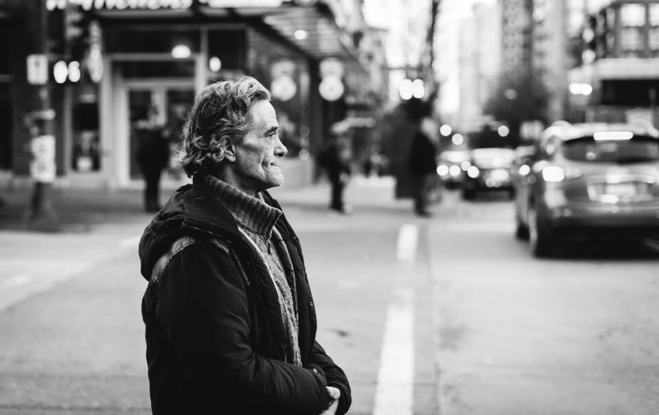 Man patiently waiting on the corner of a street with pensive peaceful demeanor